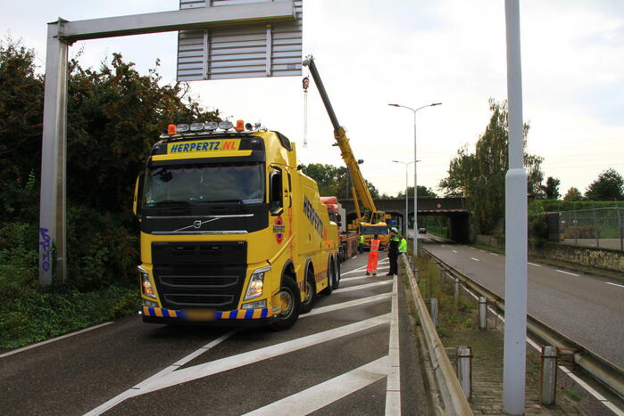 Vrachtwagen geladen met betonplaten vast onder spoorbrug