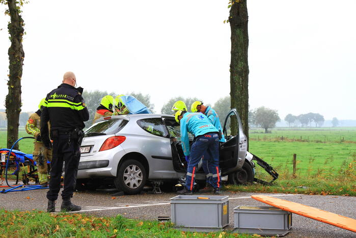 Bestuurder bekneld bij botsing tegen boom
