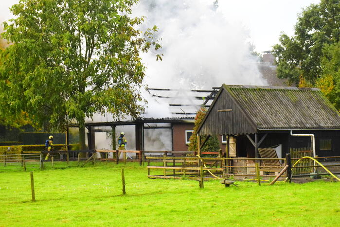 Grote brand in loods dreigt over te slaan naar woning