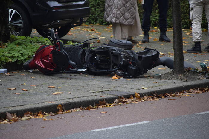 Overstekende scooter geschept door auto
