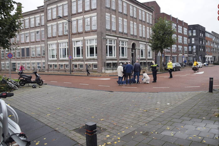 Persoon op scooter onderuit op kruising