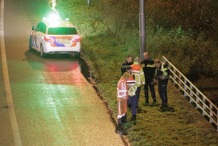 Auto belandt in water naast snelweg