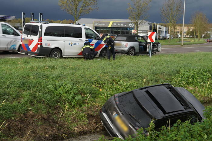 Omstanders halen inzittenden uit te water geraakt voertuig