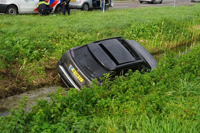 Omstanders halen inzittenden uit te water geraakt voertuig