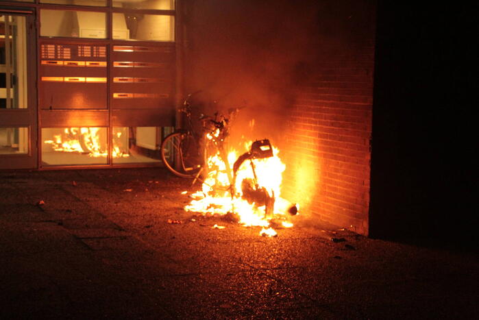 Brandweer blust brandende scooter tegen appartementencomplex