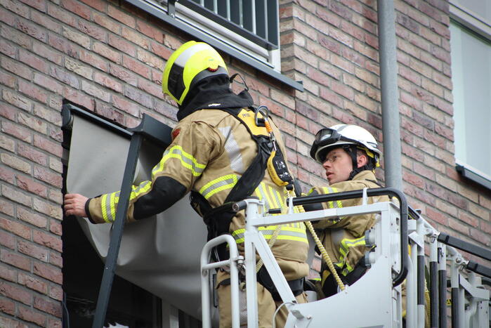 Brandweer zet loshangende zonnescherm vast