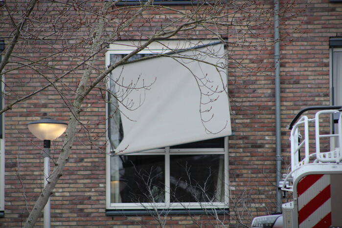 Brandweer zet loshangende zonnescherm vast