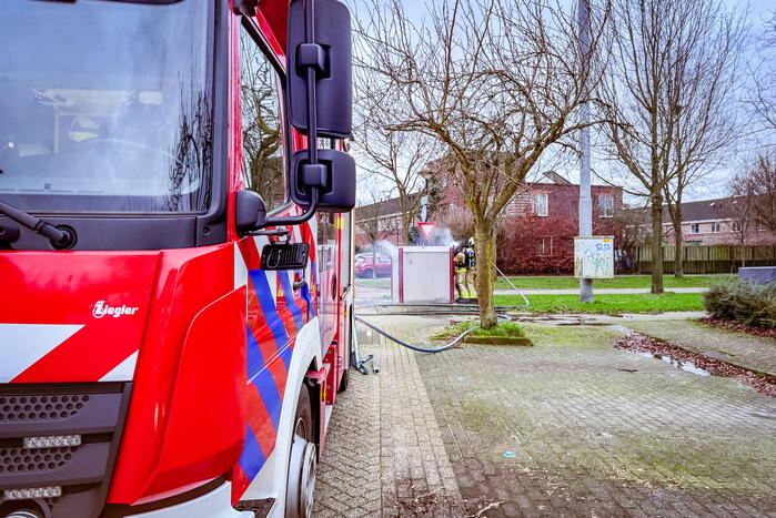 Brandweer blust brandende papiercontainer