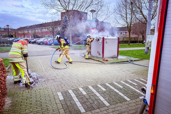 Brandweer blust brandende papiercontainer