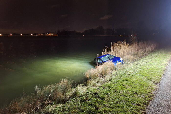Auto met twee inzittenden rolt water in tijdens 