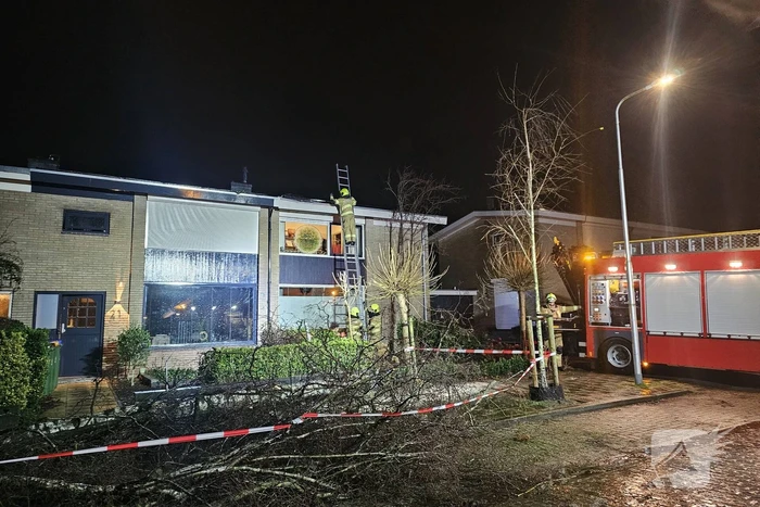 Grote boom waait om en belandt tegen woning