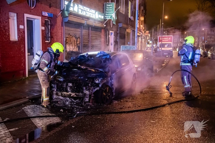 Brandweer blust in brand staande auto