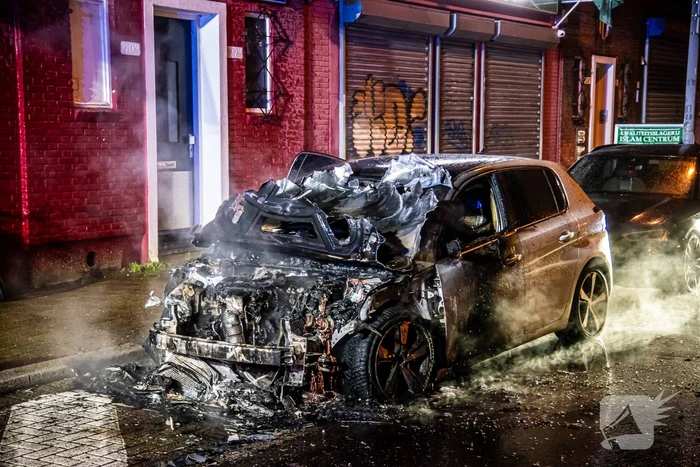 Brandweer blust in brand staande auto