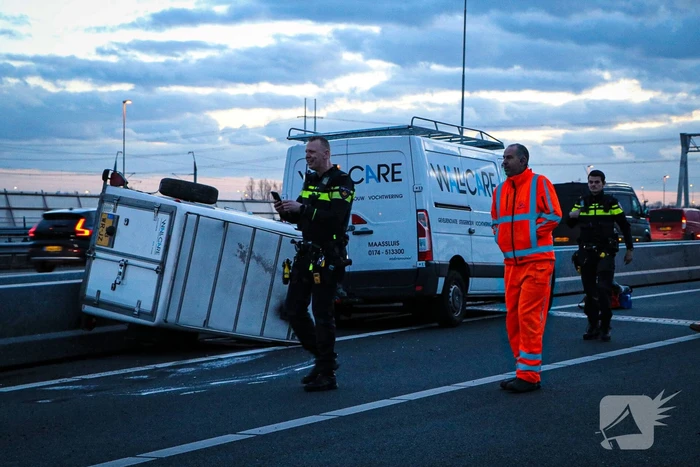 Bestelbus met aanhanger belandt op zijkant