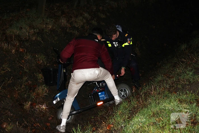 Persoon met scootmobiel in de sloot