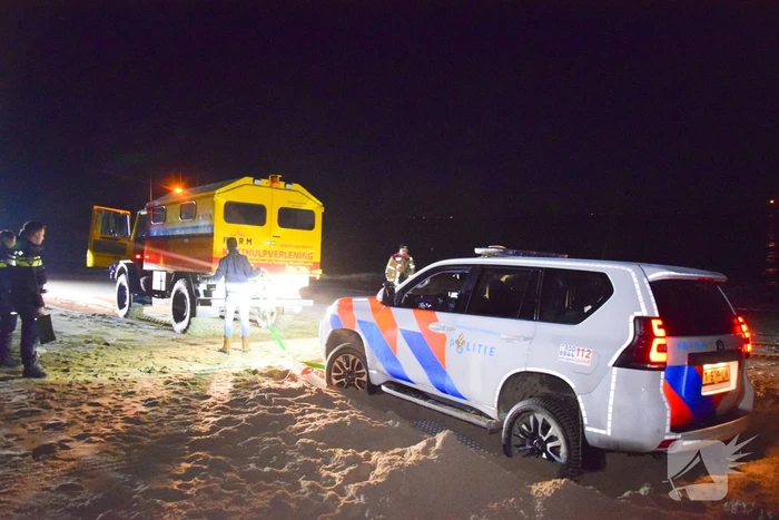 Politiejeep muurvast in los zand op strand