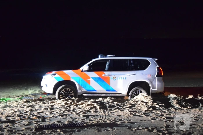Politiejeep muurvast in los zand op strand