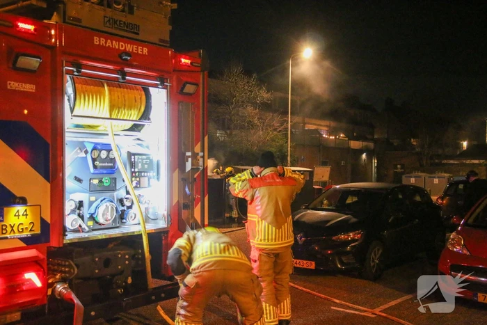 Brandweer blust brandende papiercontainer