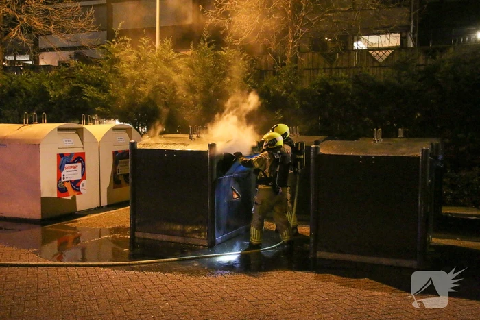 Brandweer blust brandende papiercontainer