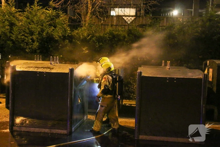 Brandweer blust brandende papiercontainer