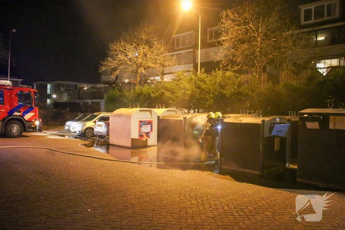 Brandweer blust brandende papiercontainer