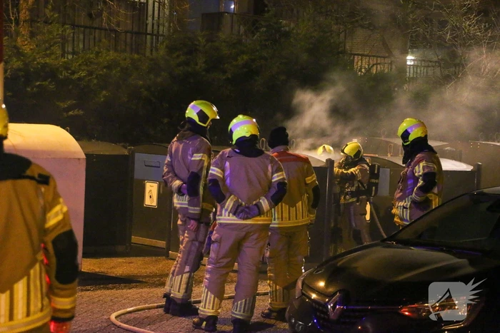 Brandweer blust brandende papiercontainer