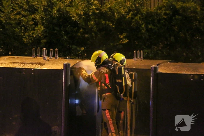 Brandweer blust brandende papiercontainer