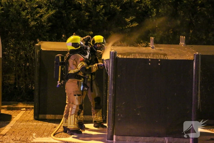 Brandweer blust brandende papiercontainer