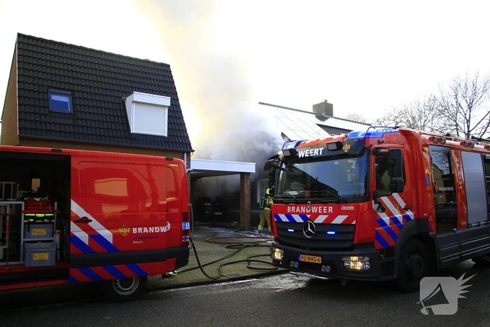 Personenauto vat vlam onder carport