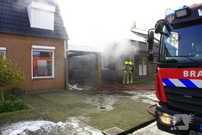 Personenauto vat vlam onder carport