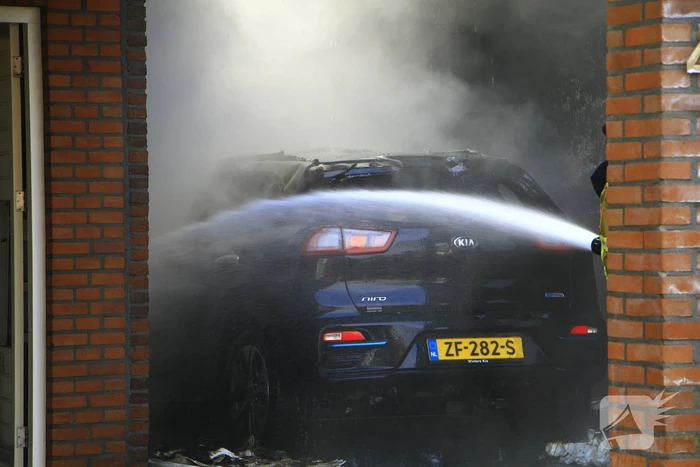 Personenauto vat vlam onder carport