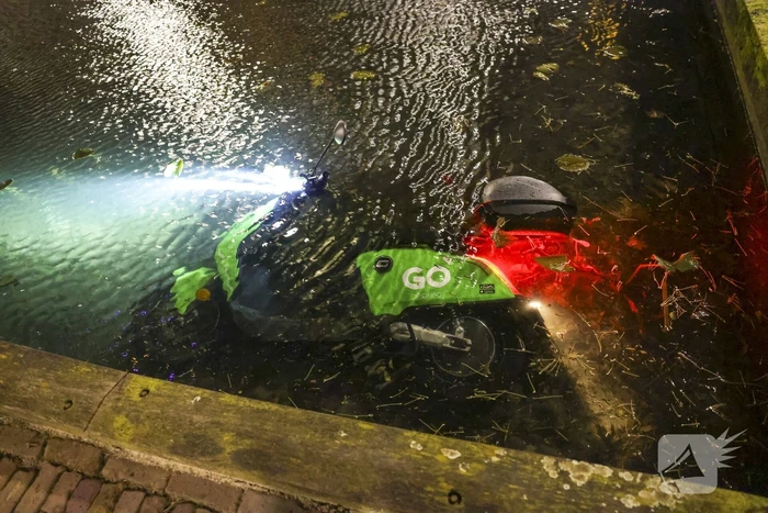Personen dumpen scooter in vijver met karpers