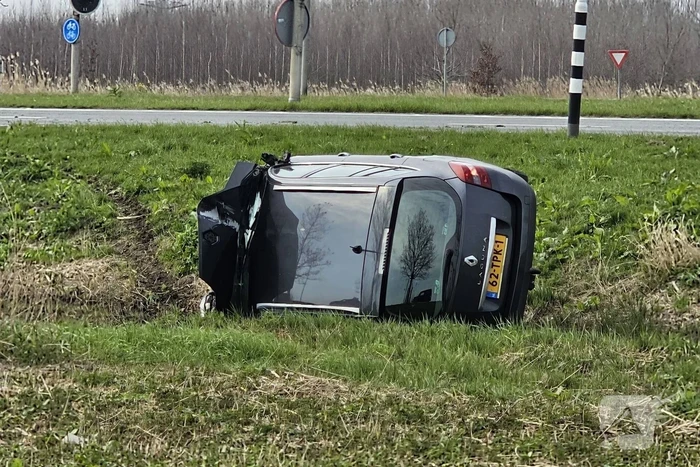 Auto ramt verkeerslicht en belandt op zijn zij in een greppel