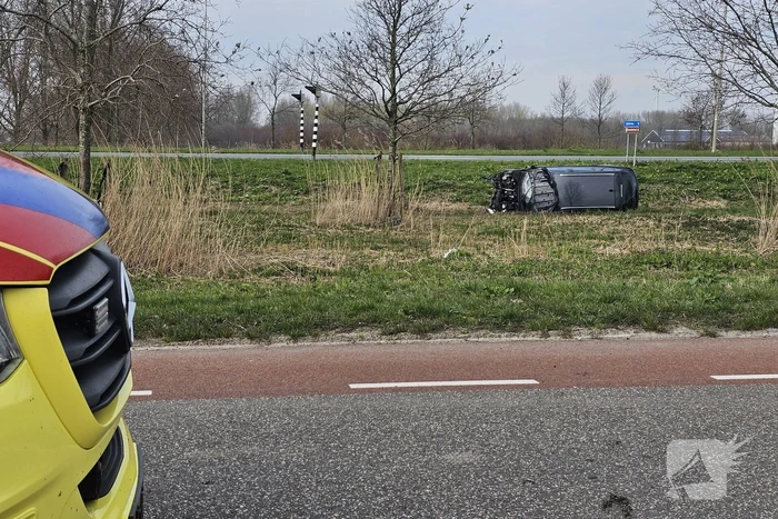 Auto ramt verkeerslicht en belandt op zijn zij in een greppel