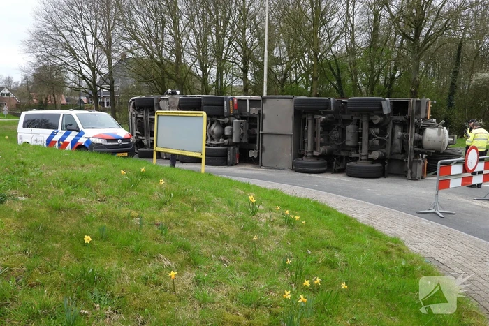 Vrachtwagencombinatie met zand kantelt op rotonde