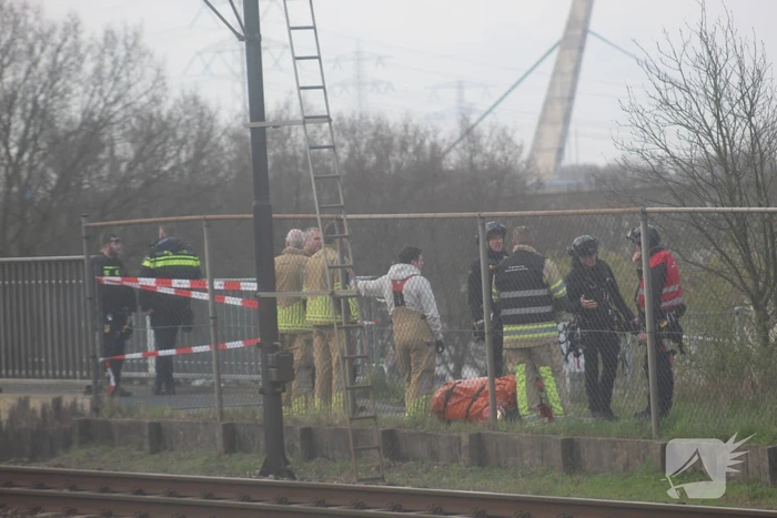 Persoon op bogen van brug, vele hulpdiensten aanwezig
