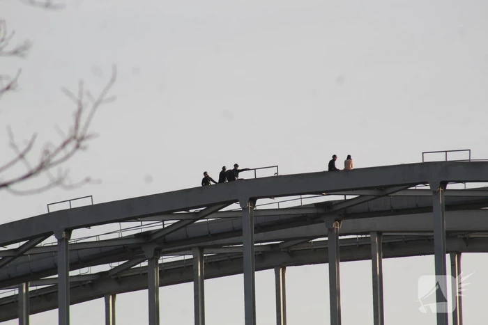 Persoon op bogen van brug, vele hulpdiensten aanwezig