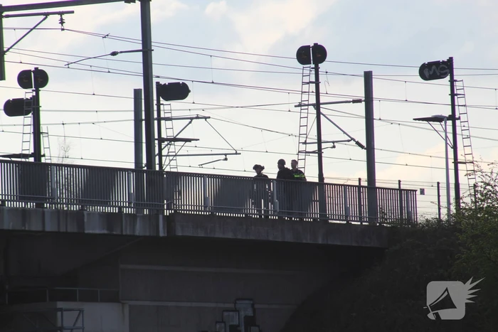 Persoon op bogen van brug, vele hulpdiensten aanwezig