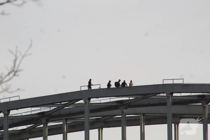 Persoon op bogen van brug, vele hulpdiensten aanwezig