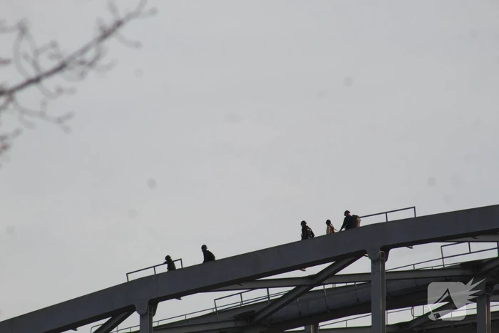 Persoon op bogen van brug, vele hulpdiensten aanwezig
