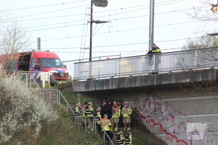 Persoon op bogen van brug, vele hulpdiensten aanwezig