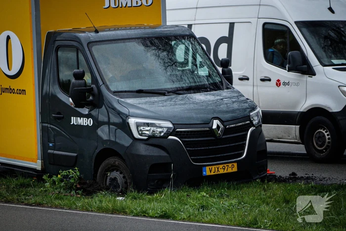 Jumbo bezorger raakt met bakwagen van weg en komt vast te zitten