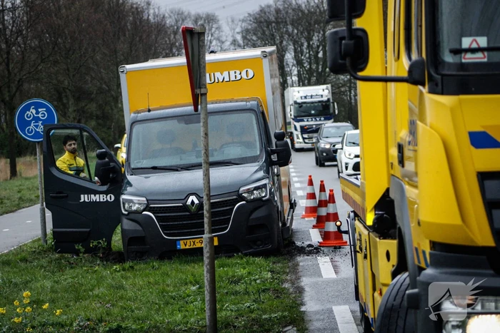Jumbo bezorger raakt met bakwagen van weg en komt vast te zitten