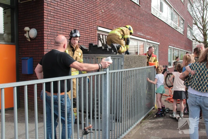 Kind bekneld tussen hek en betonnen container