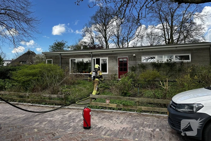 Brandweer blust brand achter woning