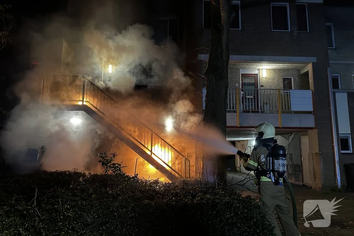 Brandweer blust brandende container onder trap