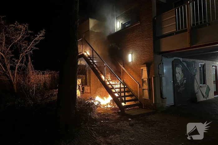 Brandweer blust brandende container onder trap