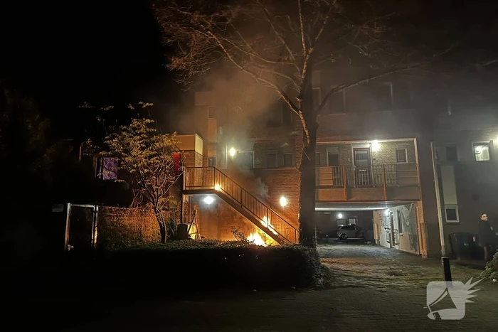 Brandweer blust brandende container onder trap