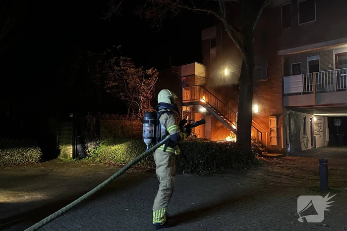 Brandweer blust brandende container onder trap