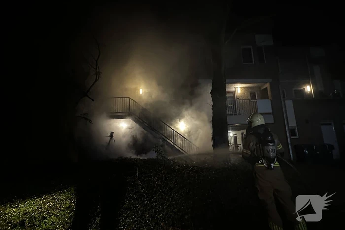 Brandweer blust brandende container onder trap